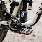 Close-up of a mountain bike's chain mechanism with visible brand logos on a blurred background.