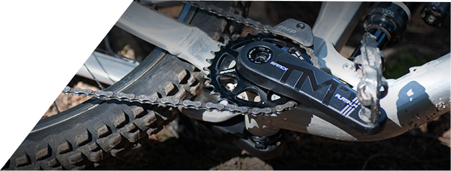 Close-up of a motorcycle chain and sprocket with 'TM' branding.