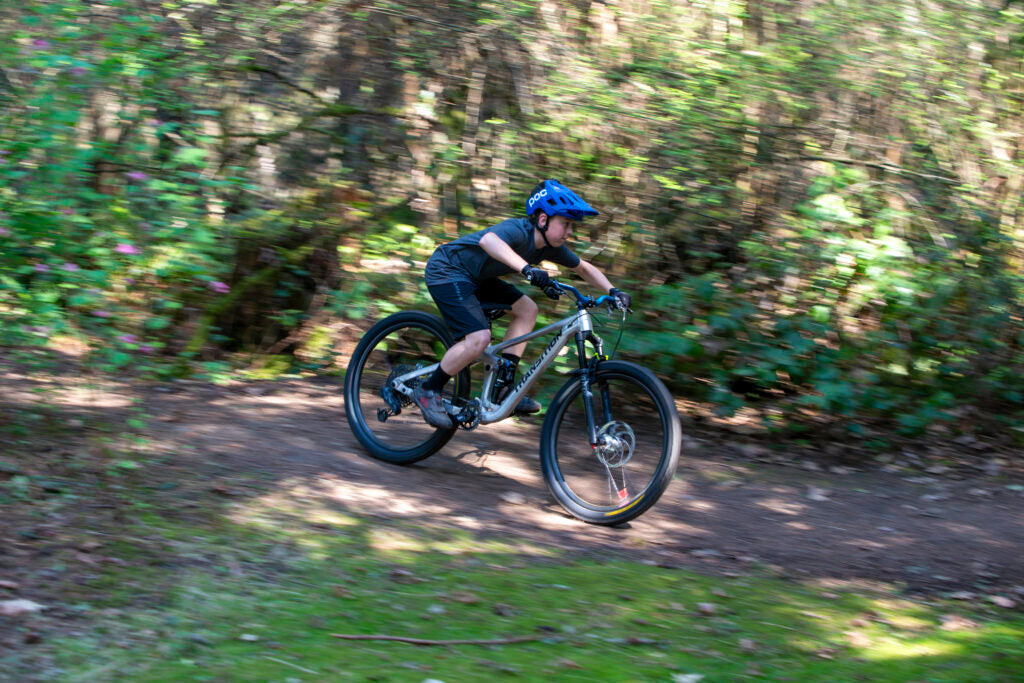 Person riding a mountain bike on a trail with greenery in the background