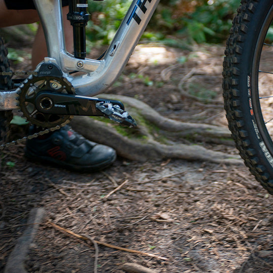 Close-up of a bike chain and gear system on a forest floor
